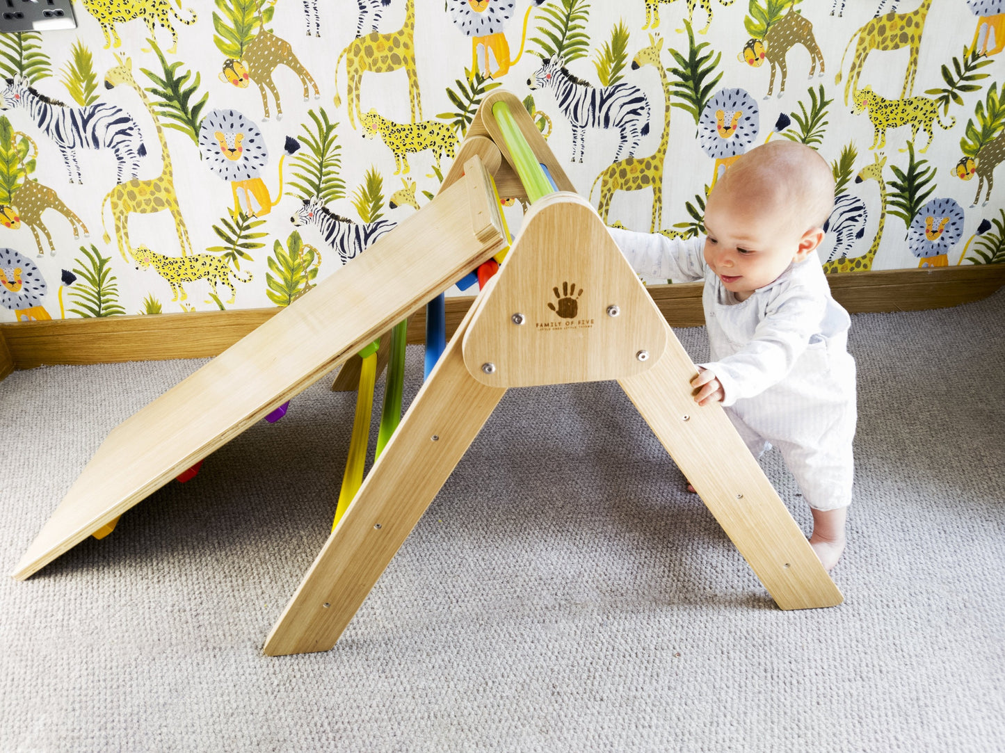 little boy holding onto a toddler climbing frame with slide