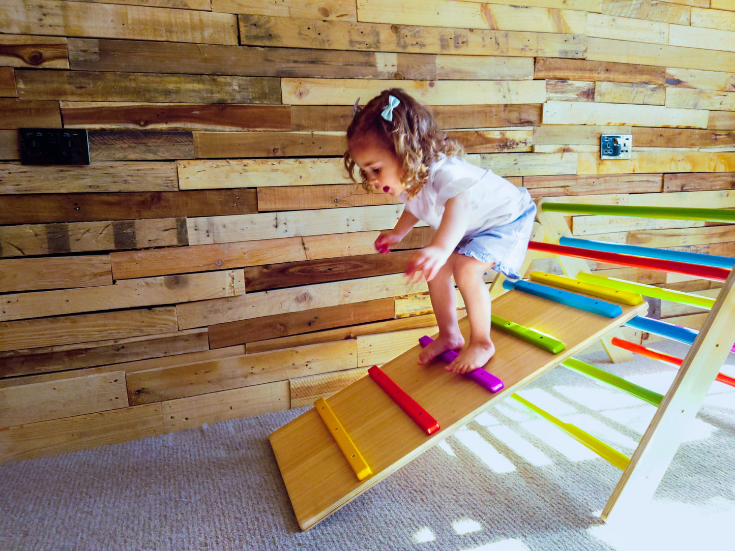 Little girl walking down ramp on a toddler climbing frame 